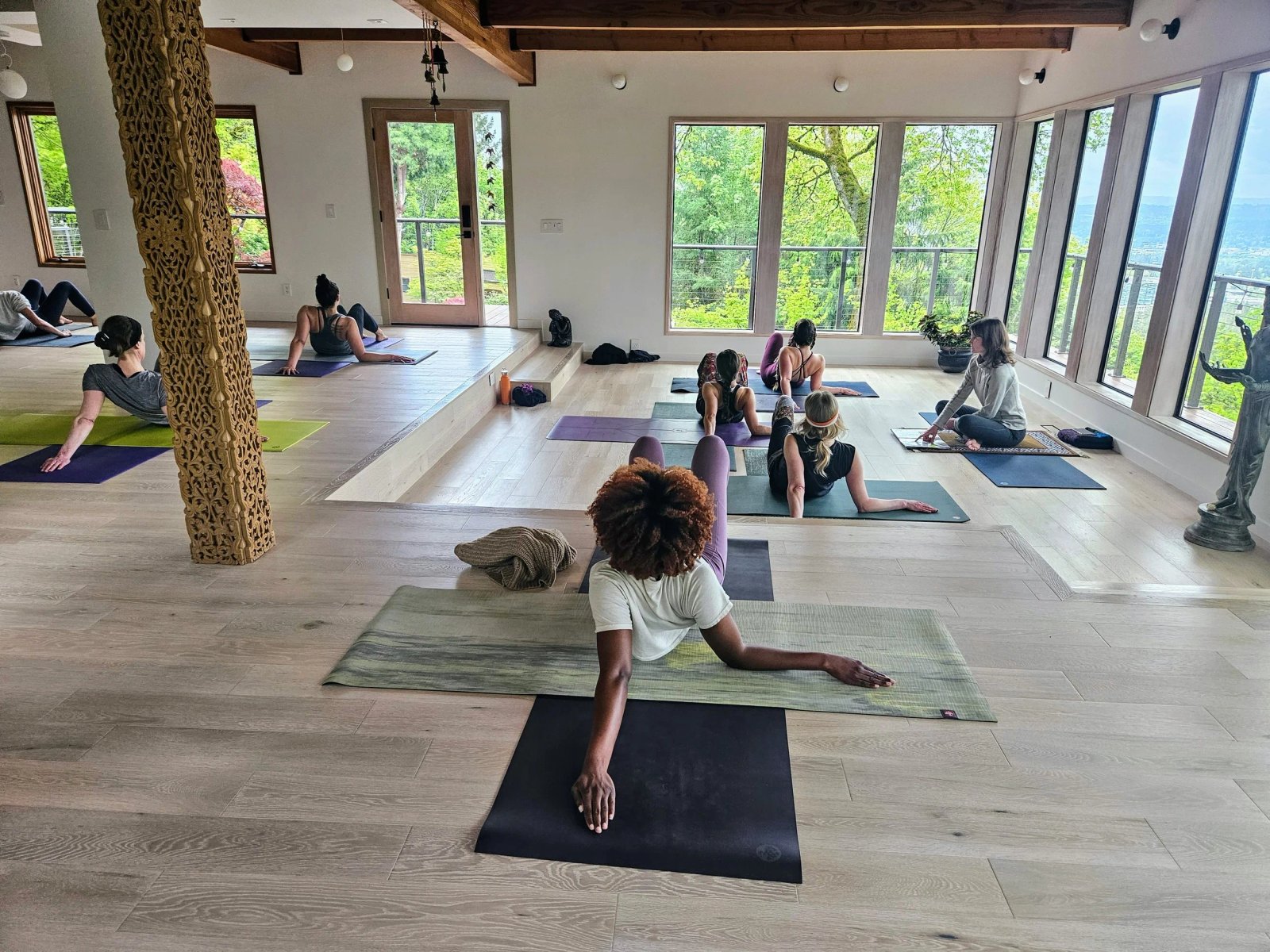 A light-filled Yoga for Life studio with a carved pillar and students practicing a twist