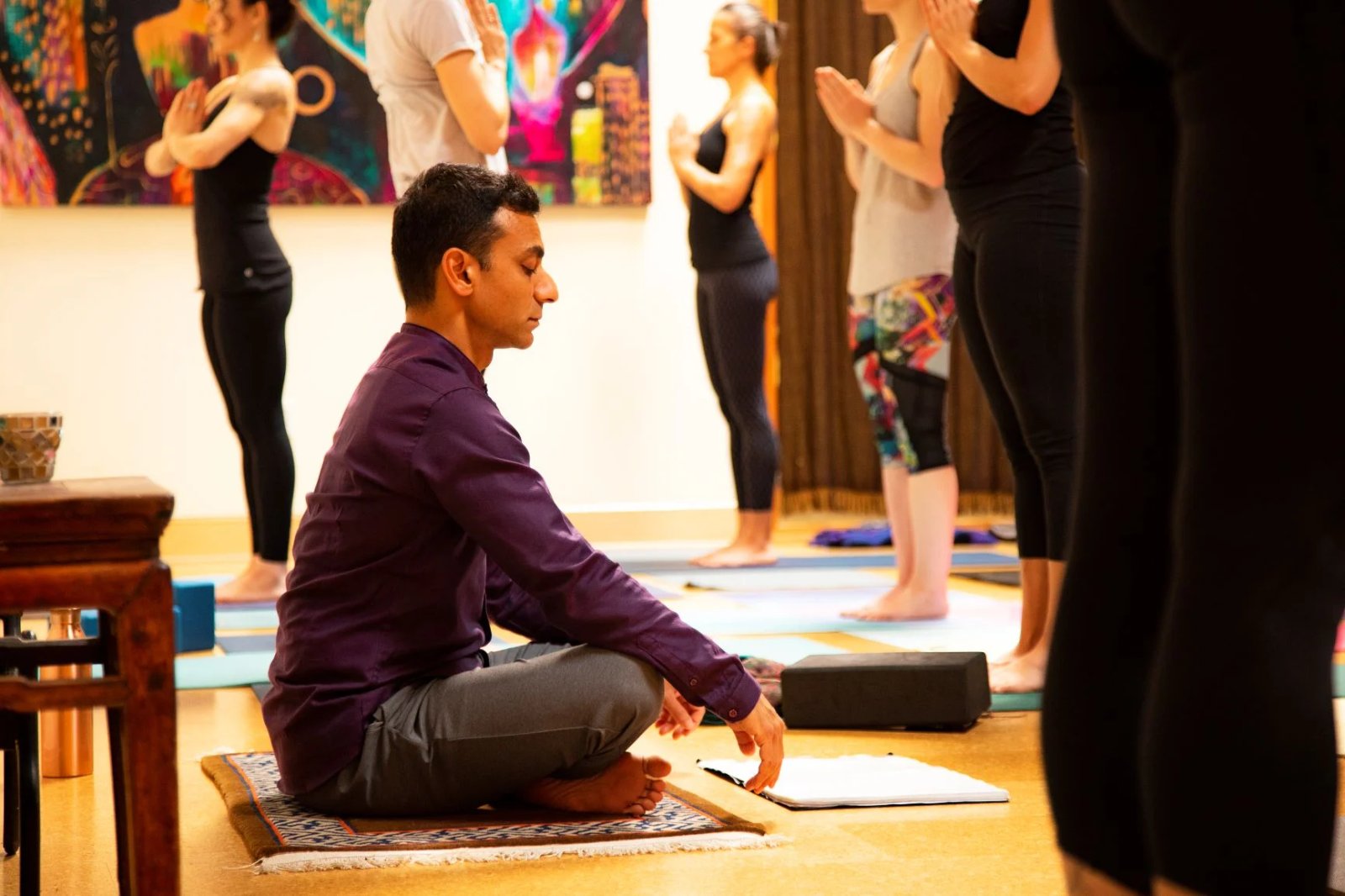 Raj teaching while yoga students stand in practice behind him