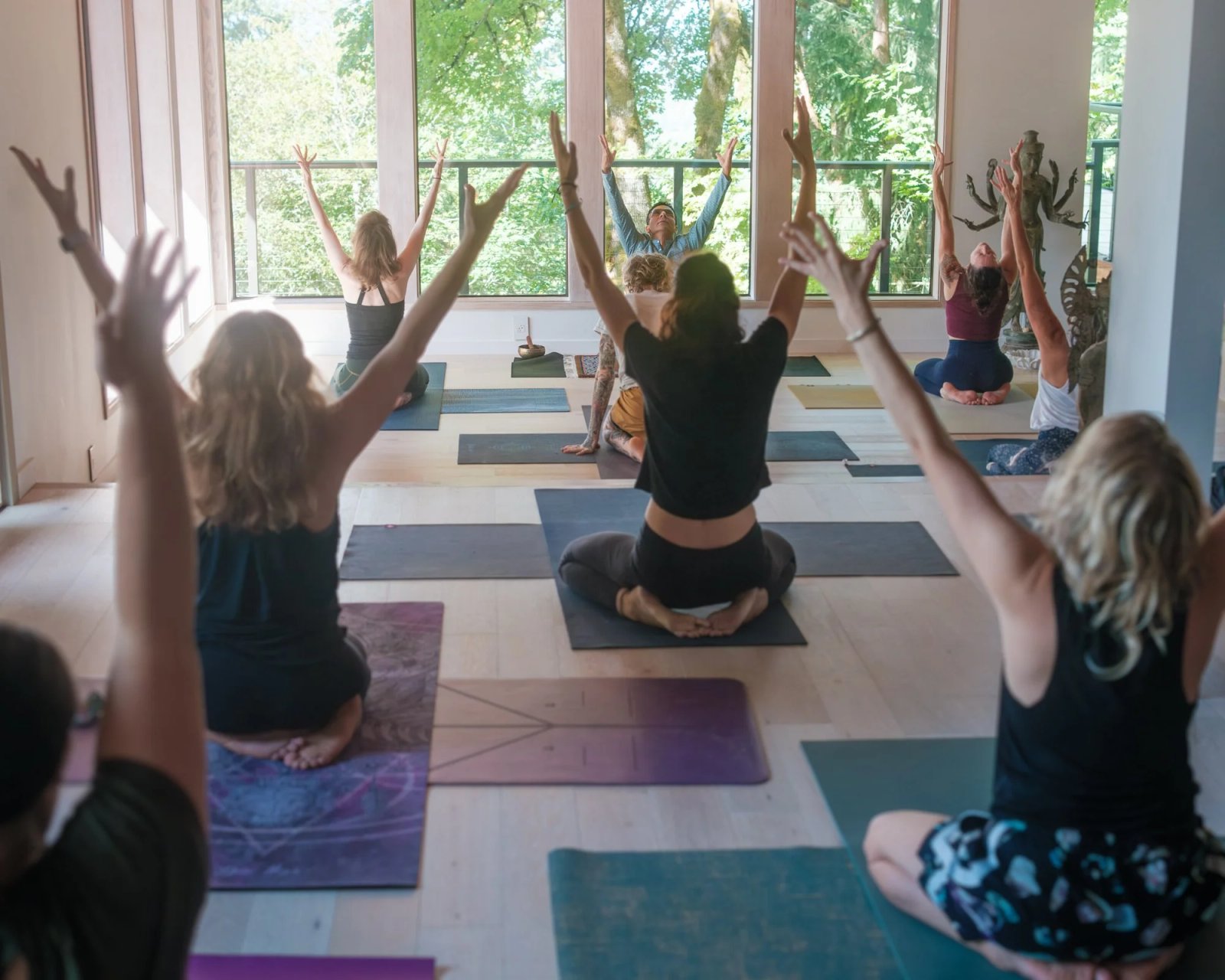 A Yoga for Life class raising their arms toward a bright studio window